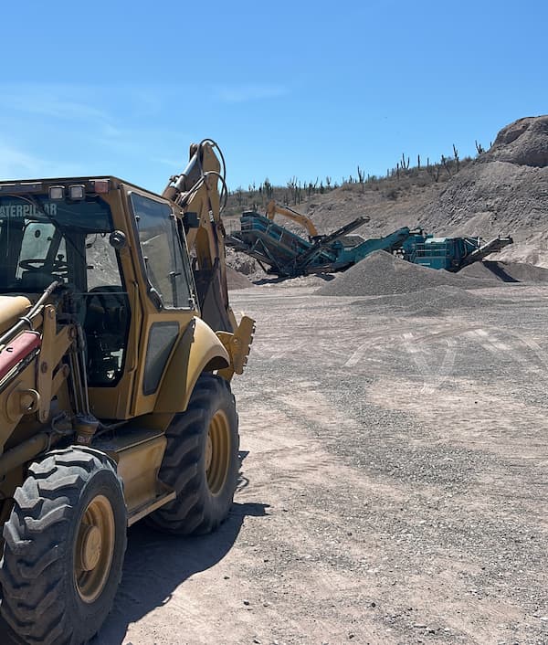 Retroexcavadora junto a criba y cono trituradores en planta de agregados, La Paz