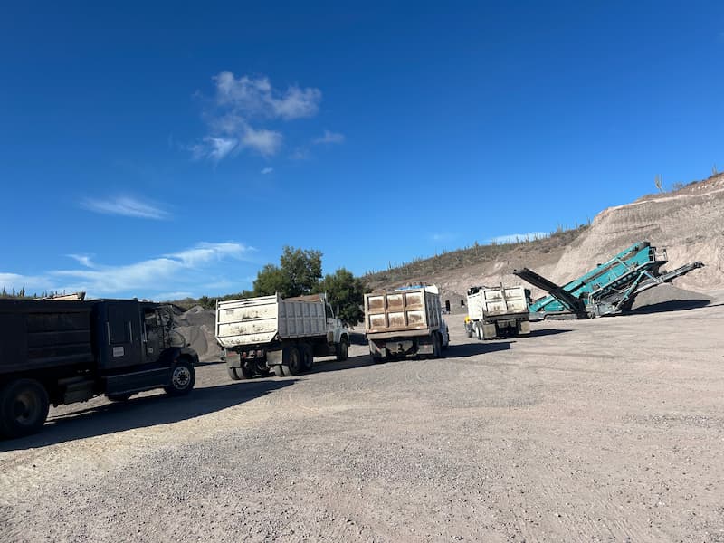 Camiones de volteo en fila esperando carga de grava triturada, DT Corporativo La Paz